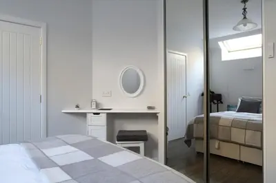 a bedroom with a bed and a desk and a mirror at Quiet Ground Floor Mews Flat and parking in Edinburgh