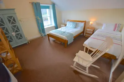 a small bedroom with two beds and a chair at Beach House - Carrick Castle in Carrick