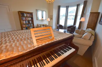 a living room with a piano and a living room with a couch at Beach House - Carrick Castle in Carrick