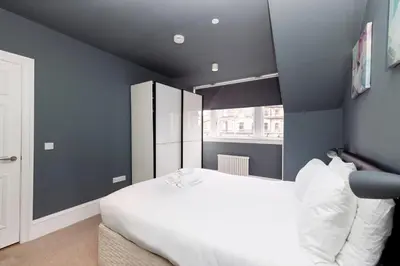 a bedroom with a white bed and a blue wall at JOIVY Spacious Apartment next to West End in Edinburgh