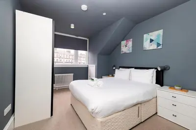 a bedroom with a large white bed and blue walls at JOIVY Spacious Apartment next to West End in Edinburgh