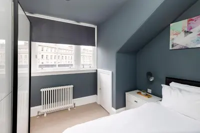 a bedroom with blue walls and a bed and a window at JOIVY Spacious Apartment next to West End in Edinburgh
