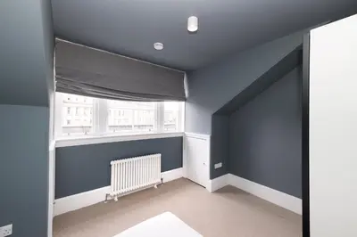 a blue room with a radiator and a window at JOIVY Spacious Apartment next to West End in Edinburgh