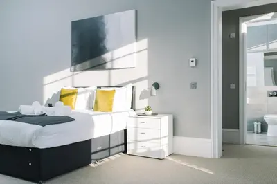 a bedroom with a large bed and a bathroom at JOIVY Modern 1 bed flat next to Haymarket Station in Edinburgh