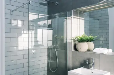a bathroom with a glass shower and a sink at JOIVY Modern 1 bed flat next to Haymarket Station in Edinburgh