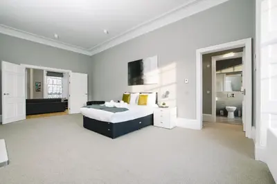 a white bedroom with a bed and a bathroom at JOIVY Modern 1 bed flat next to Haymarket Station in Edinburgh