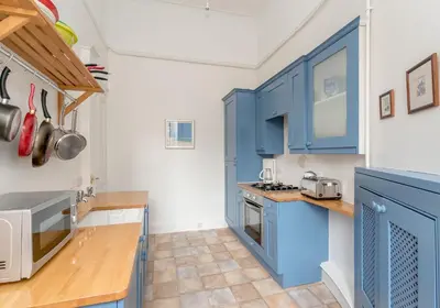a kitchen with blue cabinets and wooden counter tops at Melville Street Apartment in Edinburgh