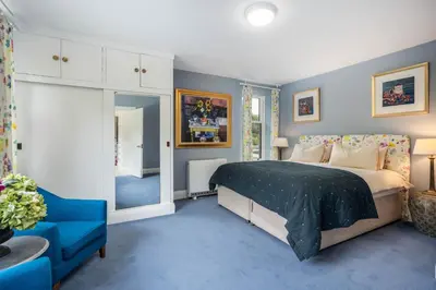 a bedroom with a large bed and a blue carpet at Crispie House in Kilfinan