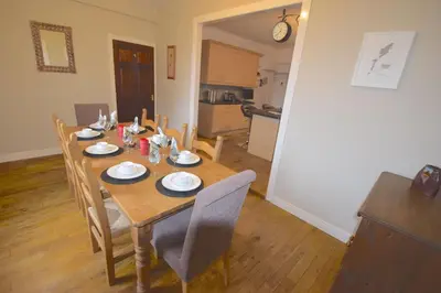 a dining room table with chairs and a kitchen at Lettermay House in Lochgoilhead