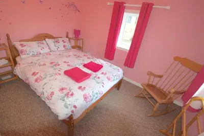 a bedroom with a bed and a rocking chair at Lettermay House in Lochgoilhead