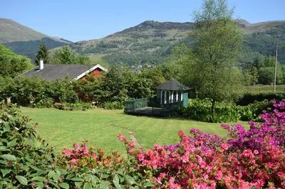 a garden with a gazebo and pink flowers at Lettermay House in Lochgoilhead