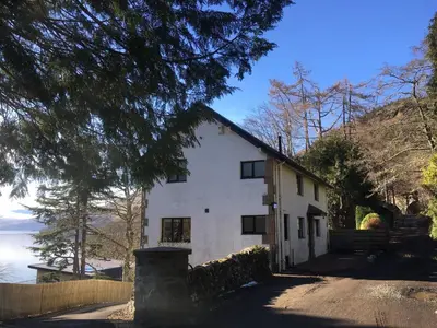 a white house with a tree in front of it at The Sheiling in Saint Fillans