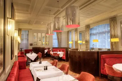 a restaurant with tables and red chairs and a bar at Hotel Indigo Glasgow by IHG in Glasgow