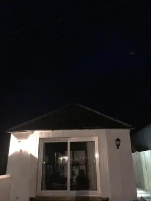 a small white house with a window at night at Carriage Cottage Hot Tub in Beith