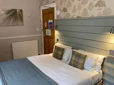 a bedroom with a bed with white sheets and pillows at Village Inn in Arrochar