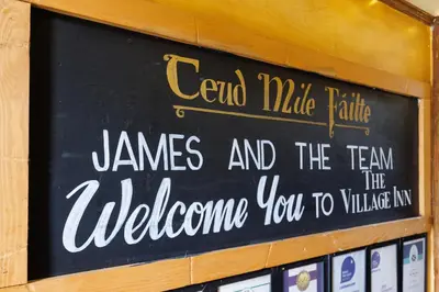 a sign that saysend mule faith james and the team the welcomes you at Village Inn in Arrochar