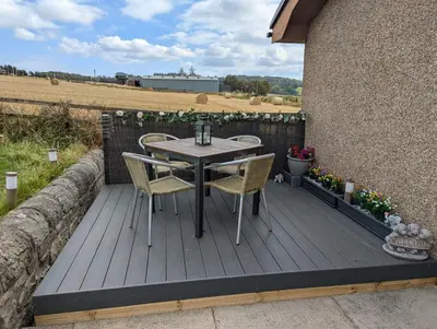 a wooden deck with a table and chairs on it at Wester Muirhouse in Linlithgow