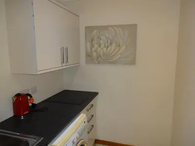 a kitchen with white cabinets and a black counter top at Wester Muirhouse in Linlithgow