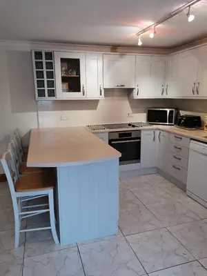 a kitchen with white cabinets and a island in it at The Greannan Lower Self catering apartment in Blackwaterfoot