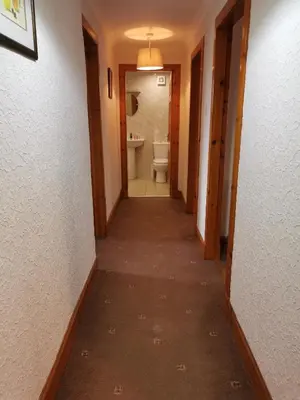 a hallway of a bathroom with a toilet and a sink at The Greannan Lower Self catering apartment in Blackwaterfoot