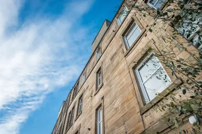 a tall brick building with windows on the side of it at The Roseburn Apartment in Edinburgh