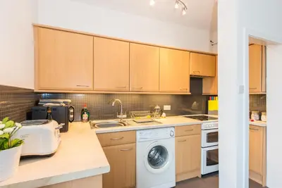a kitchen with wooden cabinets and a washer and dryer at The Roseburn Apartment in Edinburgh