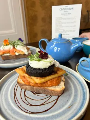 a sandwich on a plate on a table with a teapot at Crookston Hotel in Glasgow