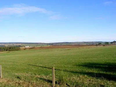 a fence in the middle of a green field at Sky Blue Cottage in Forth