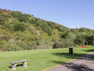a park with a bench in a grass field at Glen Euchar House in Kilninver