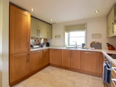 a kitchen with wooden cabinets and a sink at Muirmailing Cottage in Plean