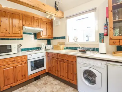 a kitchen with wooden cabinets and a washer and dryer at Darach in Lunga