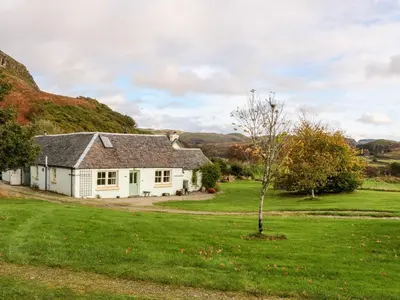 a white house with a tree in a field at Mullach in Lunga