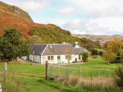 a white house with a fence and mountains in the background at Mullach in Lunga