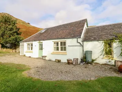 a white cottage with a bench in front of it at Mullach in Lunga