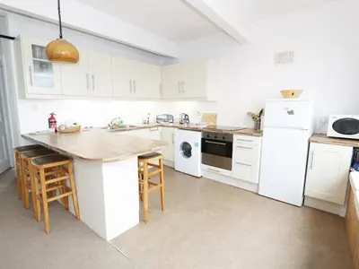 a kitchen with white cabinets and a wooden counter top at Top Flat in Tighnabruaich