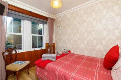 a bedroom with a red bed and a window at Castle Walk Bed & Breakfast in Stirling