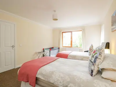 a bedroom with two beds and a window at Woodland Villa in Oban