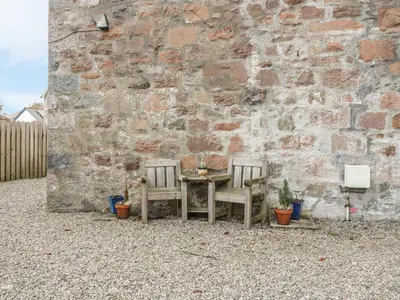 a table and two chairs in front of a brick wall at The Knowe Upper in Taynuilt