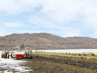a boat is docked on the beach next to the water at The Knowe Upper in Taynuilt