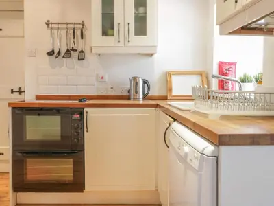 a kitchen with white cabinets and a wooden counter top at Sweetpea Cottage in Wiston