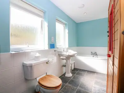 a bathroom with a toilet and a sink and a tub at Poppies Cottage in Craignure