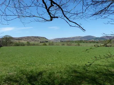 a field of green grass with mountains in the background at Tulchan Lodge in Buchanty