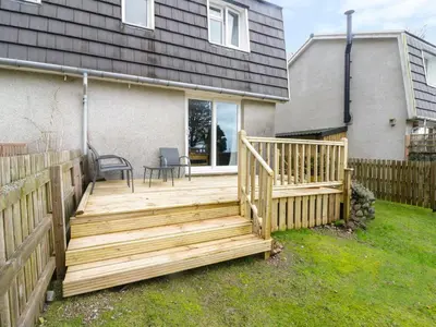 a wooden deck in front of a house at Pebble Nook in Onich
