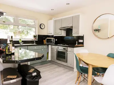 a kitchen with white cabinets and a wooden table at Pebble Nook in Onich