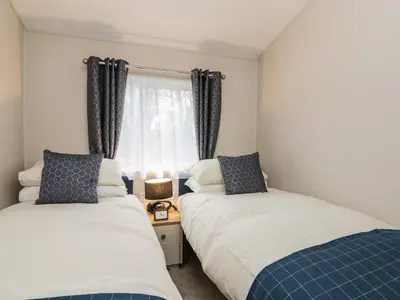two beds in a room with a window at Woodstock Lodge in Skelmorlie