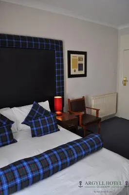 a hotel room with two beds and a chair at Argyll Guest House in Glasgow