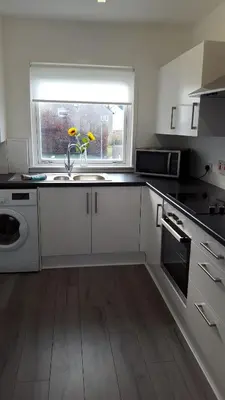 a white kitchen with a sink and a window at Flemming Place in East Kilbride