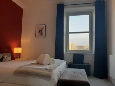 a bedroom with a teddy bear sitting on a bed with a window at Stylish City Apartment - Near Haymarket, Walk to Castle and Princes Street in Edinburgh