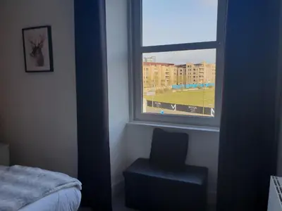 a bedroom with a window with a chair and a bed at Stylish City Apartment - Near Haymarket, Walk to Castle and Princes Street in Edinburgh