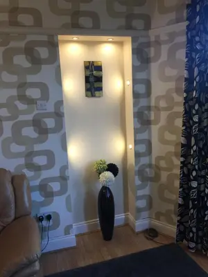 a vase with flowers in a room with a wall at Scotstoun 1 Bed Flat in Glasgow
